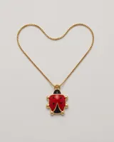 Collar de bronce con cadena fina dorada y un dije colgante en forma de mariquita con detalles esmaltados en rojo y negro.