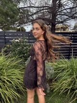 Vestido corto de encaje marrón, con escote en V, corte debajo del busto, mangas largas estilo trompeta y espalda transparente con volado en el ruedo.