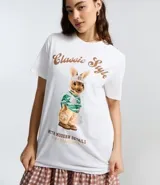 Remera de algodón color blanco, con cuello redondo y mangas cortas. Presenta un bordado central de un conejo vestido con ropa deportiva y gorra, acompañado de la frase 'Classic Style' en la parte superior y 'With Modern Details' en la parte inferior.