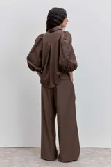 Camisa de color marrón con cuello clásico, mangas abullonadas y detalle de bordado floral en una de las mangas.