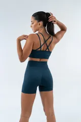 Top deportivo de tejido seamless, color azul petróleo, con escote recto y espalda con tiras cruzadas.