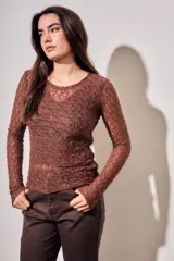 Remera de encaje negro ajustada al cuerpo, de manga larga y diseño transparente.