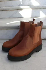 Bota tipo chelsea de cuero color chocolate, con paneles laterales elásticos y suela track de goma negra.
