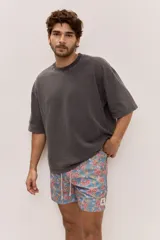 Short de baño celeste con estampa tropical de flores, cintura con cordón ajustable y detalle de etiqueta textil en el lateral.