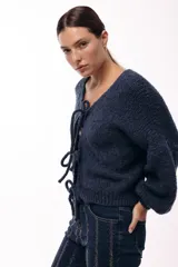 Saco tejido de punto color azul, con escote en V y cierre frontal mediante lazos. Presenta mangas largas amplias con puños ajustados y un calce relajado.