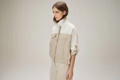 Chaquetas de lino bicolor en tonos blanco y beige, con diseño holgado, cuello alto, cierre frontal de botones, bolsillos con solapa en el pecho y mangas cortas con presilla y botón.