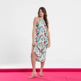 Vestido midi con estampado de hojas en tonos celeste, verde, rojo y rosa. Tiene cuello halter y corte evasé con abertura lateral.