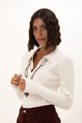Sweater de tejido de punto fino color blanco, con cuello polo y escote en V, de manga larga y ajuste al cuerpo.