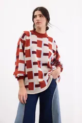 Sweater de tejido de punto con diseño geométrico a cuadros en tonos beige, terracota, bordó y celeste, de corte holgado, manga larga y cuello redondo.