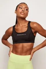 Top deportivo negro de alto rendimiento, con tirantes medianos, espalda baja y diseño con bolsillos internos para copas removibles.