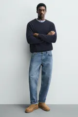 Bota de caña corta fabricada en piel con acabado serraje, con detalle de costura en el empeine, forro interior de pelo sintético y suela plana a tono.