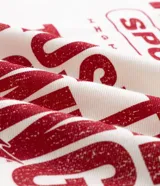 Remera oversized de color blanco marfil con detalles en rojo, cuello redondo, mangas cortas y grandes estampas tipográficas y gráficas en la espalda.