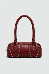 Cartera tipo baguette color granate, de diseño alargado, con detalles de tachas metálicas plateadas y asas de hombro.