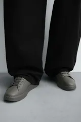 Zapatillas urbanas de cuero sintético negro, con cordones y suela gruesa monocolor.