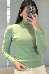 Buzo de tejido de punto fino en color verde, con cuello medio y mangas largas, de corte ajustado al cuerpo.
