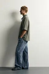 Jeans de denim de algodón en color azul con efecto desgastado, tiro medio y corte recto de ajuste holgado (loose fit). Cuenta con diseño clásico de cinco bolsillos y cierre frontal con cremallera y botón.