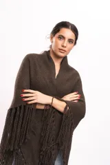 Ruana marrón oscuro tejida en punto texturizado, con cuello envolvente y bordes decorados con flecos largos colgantes.