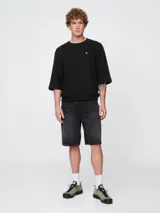 Remera de corte oversized en color beige claro, con cuello redondo y mangas de largo medio. Presenta un pequeño bordado del oso Brannan de Gap en el lado izquierdo del pecho.