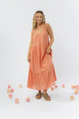 Vestido largo de corte amplio con breteles finos y escote en V. Presenta un diseño escalonado con volados en el ruedo que aportan movimiento. Confeccionado en gasa de algodón liviana con textura.