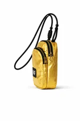 Cartera bandolera pequeña color dorado metálico, con cierre principal y bolsillo frontal con cierre. Tiene una correa ajustable de cordón negro y un parche rectangular negro con el logo "IND" en blanco.
