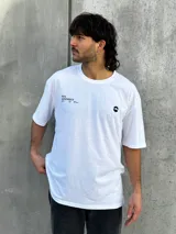 Remera blanca de corte oversize con estampado en la espalda que incluye dos círculos intersecados con las palabras 'Surf', 'Life' y 'Skate', y las frases 'Real Experience', 'Coexist' y 'Meaningful Day'.