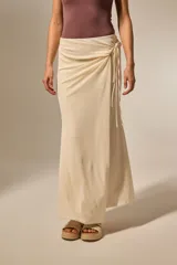 Falda larga de corte envolvente en color natural, con detalle de anudado lateral y caída fluida.