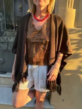 Ruana tejida en color chocolate con diseño abierto, mangas cortas y terminaciones con flecos en el ruedo.