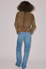 Jeans de tiro medio con corte bootcut, confeccionados en denim azul con efecto lavado y ligeros desgastes. Presentan diseño de cinco bolsillos, trabillas en la cintura y cierre frontal con cremallera y botón.