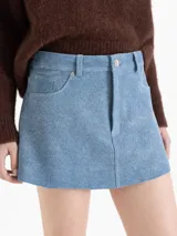 Minifalda de cuero ovino color azul, con terminación símil denim. Cuenta con bolsillos plaqué en la parte trasera y remaches tipo jeaneros. El acceso es mediante cierre y botón metálico.