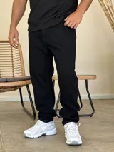 Pantalón jean de corte recto y holgado, color negro, con diseño de cinco bolsillos y cierre frontal con botón y cremallera.