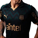 Camiseta de fútbol Puma del Club Atlético Peñarol, modelo Third Jersey 26. Diseño en tonos oscuros con patrón geométrico en zigzag, detalles en color dorado en cuello, mangas y logos. Incluye escudo del club, logo de Puma y sponsor Antel en el frente.