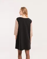 Vestido corto negro con mangas 3/4 verdes, cuello bote y bolsillos laterales.