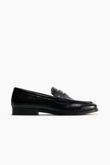 Mocasines estilo penny de color negro, con costura tradicional en la parte delantera y suela baja.
