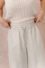 Pantalón de denim liviano color beige, de calce amplio y relajado con pierna recta. Cuenta con cintura elastizada, cordón regulable, bolsillos laterales y costuras delanteras verticales que estilizan la silueta.