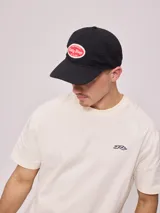 Gorra de lona lavada color beige con visera azul marino y parche bordado con el logo de Rusty.