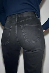 Jeans mom fit de tiro alto color negro con efecto lavado, diseño de cinco bolsillos y corte tobillero.