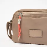 Bandolera color beige con correa larga regulable, cierre superior y bolsillo frontal con cierre.