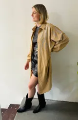 Camisola larga color beige con apliques de strass plateados, cuello camisero, mangas largas con puños abotonados y cierre frontal con botones. Puede usarse como vestido o sobrecamisa.