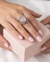 Anillo de plata 925 con piedra de cuarzo rosa natural en forma ovalada, rodeada por un diseño de pequeñas esferas metálicas.
