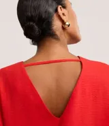 Blusa Cortelle de corte holgado confeccionada en crepé, con escote en V delantero y trasero, y mangas cortas. Presenta una tira decorativa entre los hombros en la espalda.