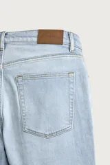 Jeans slim fit de tiro medio, color celeste claro con efecto lavado. Confeccionados en tejido elástico, cuentan con diseño de cinco bolsillos y cierre frontal con cremallera y botón metálico.