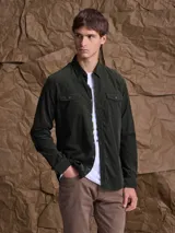 Camisa de pana de manga larga en color verde oscuro, con cuello clásico, cierre frontal de botones y dos bolsillos con solapa en el pecho.