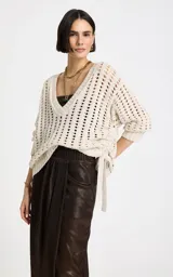 Sweater beige de punto calado con escote en V profundo, mangas largas holgadas con puños acanalados y detalle de lazo ajustable en el lateral.