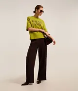 Remera verde de mangas cortas, confeccionada en malla, con cuello redondo y lettering "happy hour" estampado en el pecho.