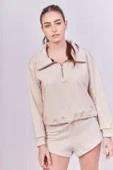 Buzo color arena de rústico de algodón, con cuello polo con cierre metálico y reguladores en el ruedo.