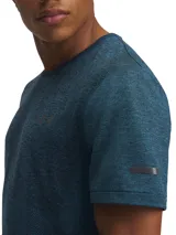 Remera deportiva Under Armour azul con diseño jaspeado, logo en el pecho y detalle reflectivo en la manga.