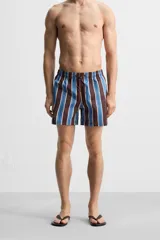 Short de baño confeccionado en tejido técnico con diseño de rayas verticales en tonos azul, marrón y beige. Cuenta con cintura elástica ajustable con cordón, bolsillos laterales y forro interior.