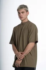 Remerón de jersey pesado color verde oliva, con cuello redondo y manga corta. Presenta un estampado sutil en el pecho y un estampado más grande en la espalda.