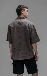 Camisa de manga corta con calce oversize y cuello abierto, confeccionada en algodón con diseño de bordado tipo broderie y efecto de desgaste en el color.