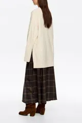 Sweater de punto negro con efecto tweed o neps en color dorado/amarillo claro, cuello alto tipo caja y mangas largas. Corte recto y holgado.